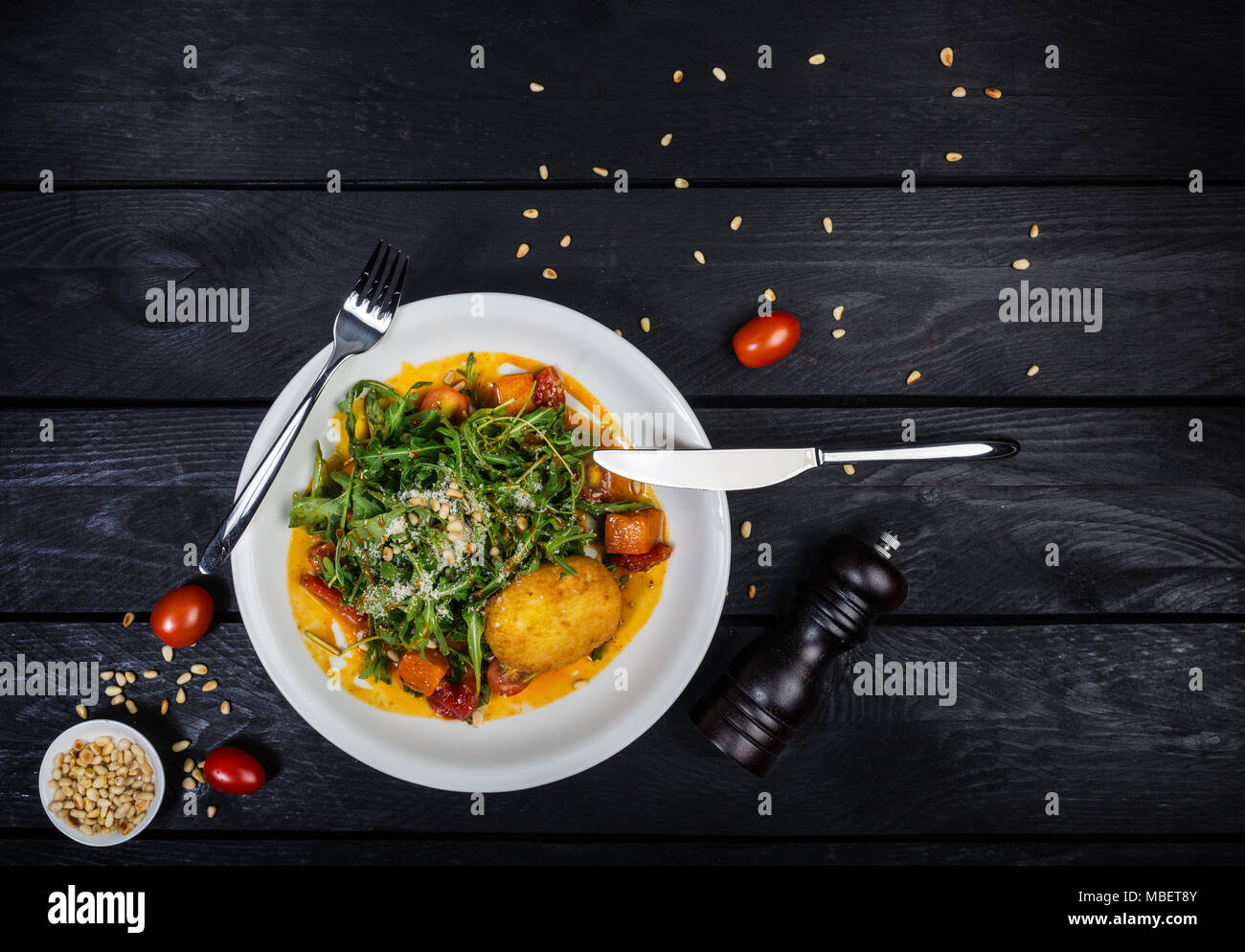 Arugula salad with baked pumpkin and pine nuts in the sea-buckthorn sauce. Stock Photo