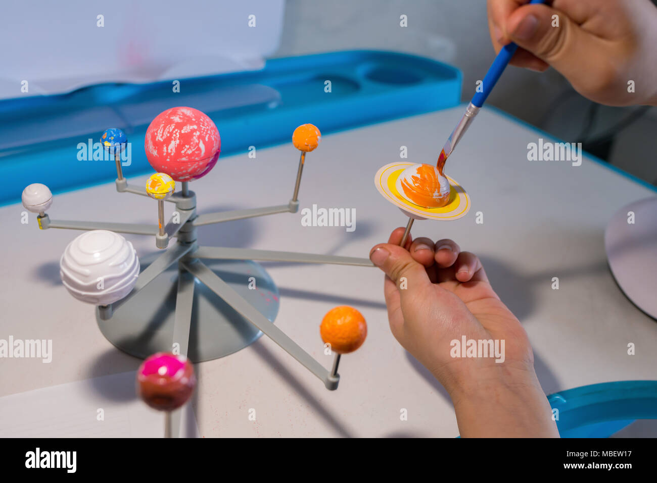 kid painting the Saturn on a Solar System model Stock Photo