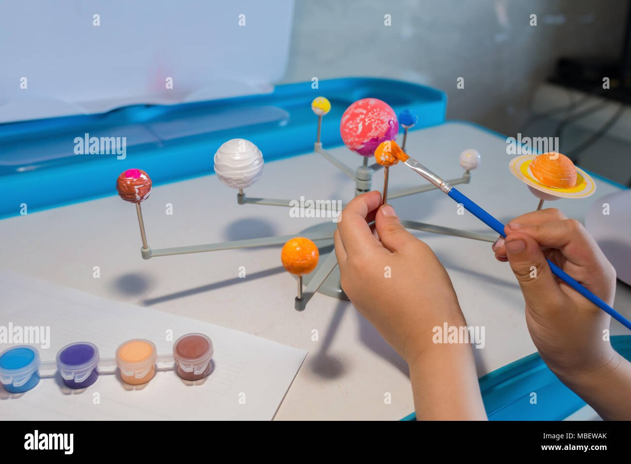kid painting the Earth on a Solar System model Stock Photo