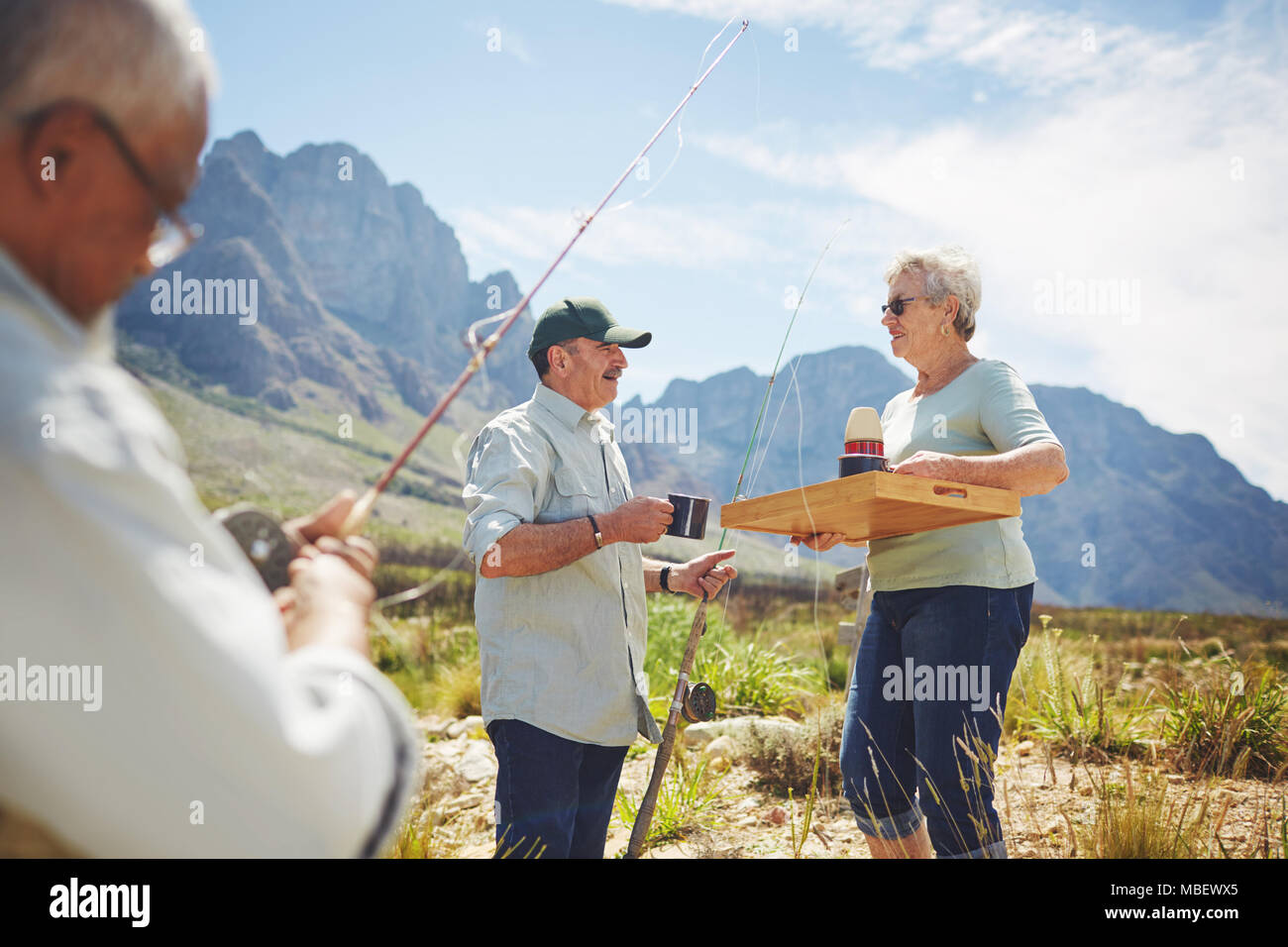 Active senior woman serving coffee to husband fishing Stock Photo