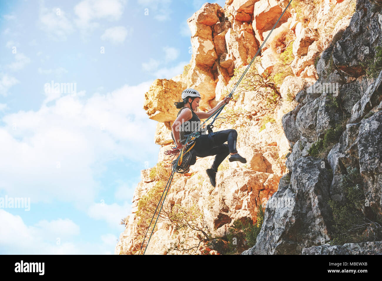Female rock climber descending rocks Stock Photo