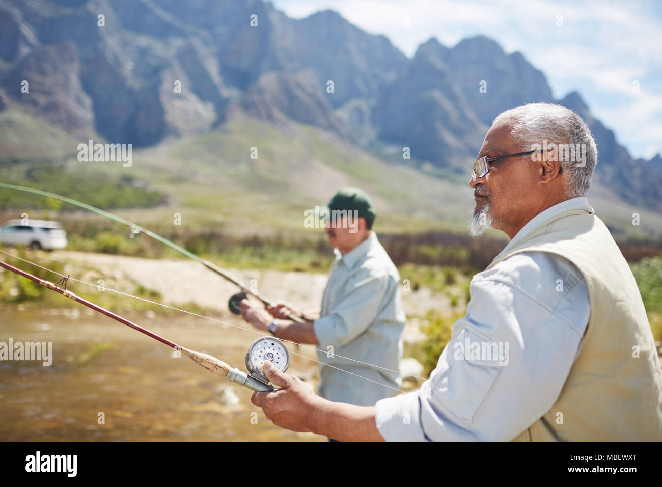 Active senior men friends fishing at sunny summer lakeside Stock Photo