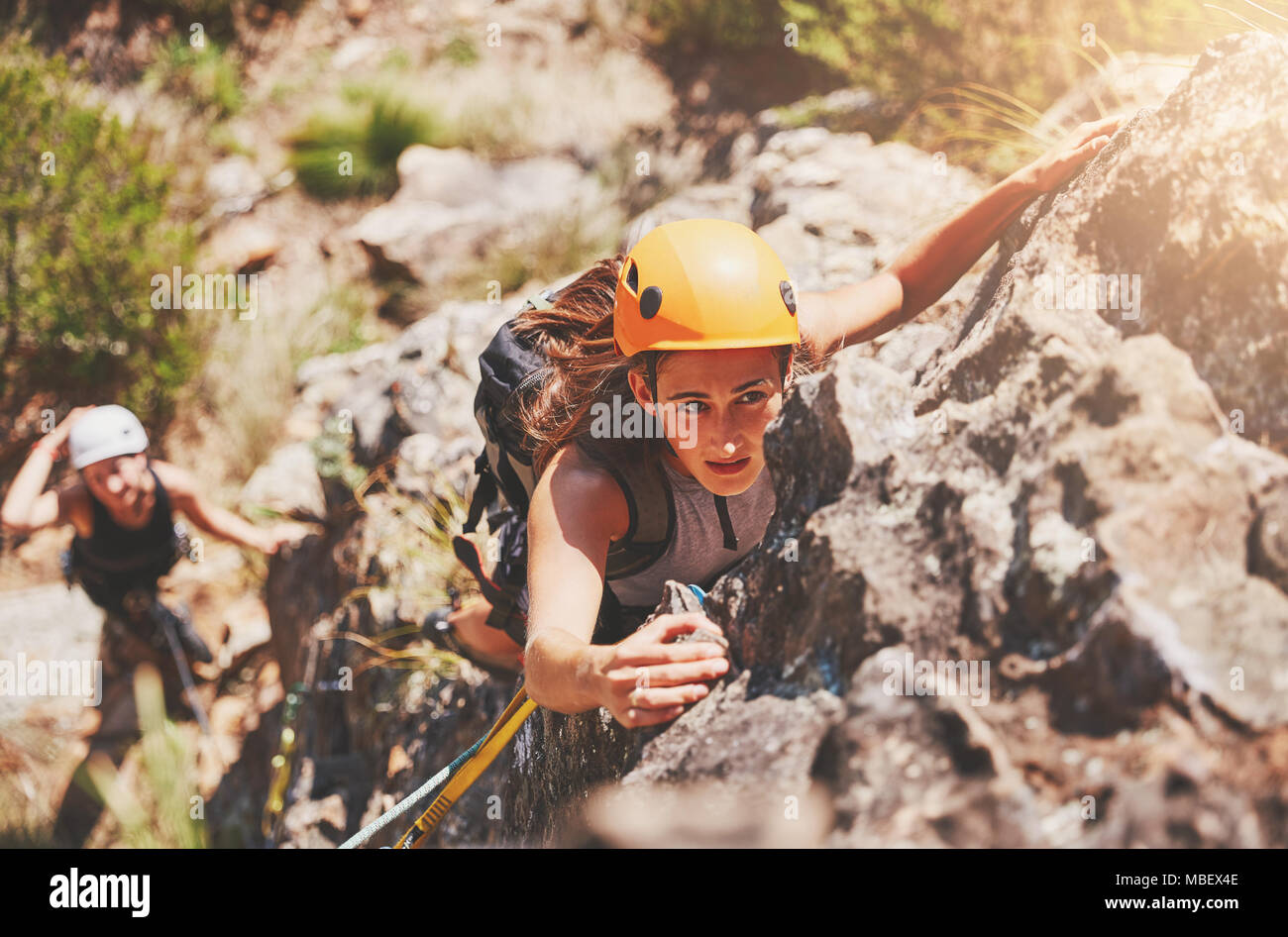 Focused, determined female rock climber hanging from rock Stock Photo