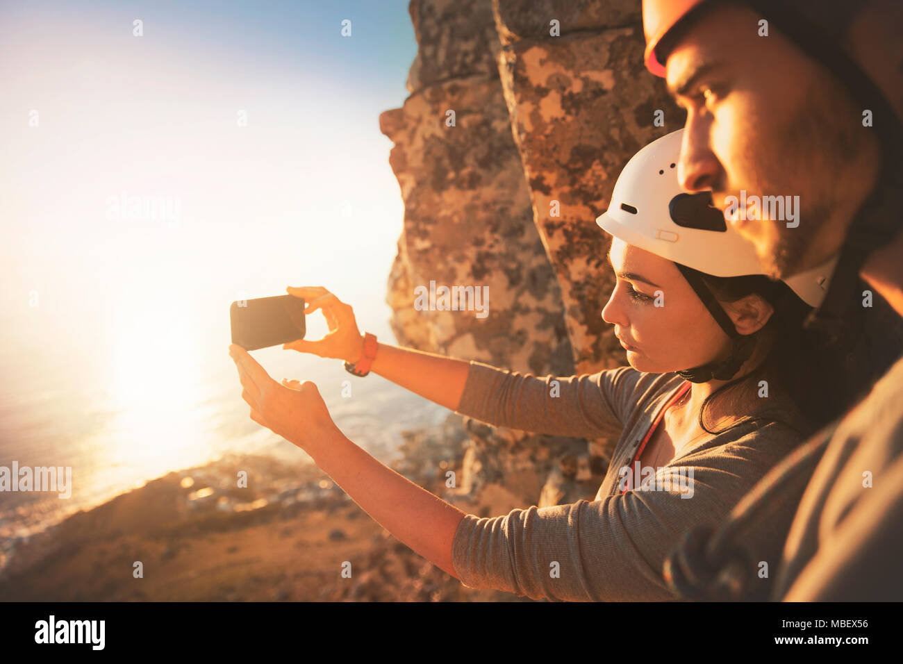 Rock climbers with camera phone photographing ocean view Stock Photo