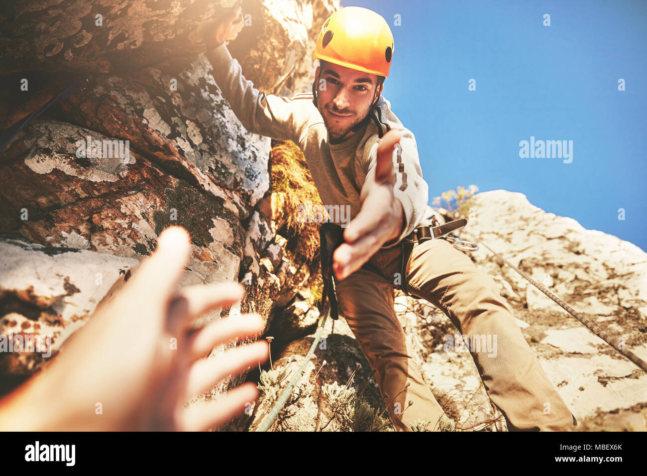 Personal perspective reaching for hand of rock climber Stock Photo