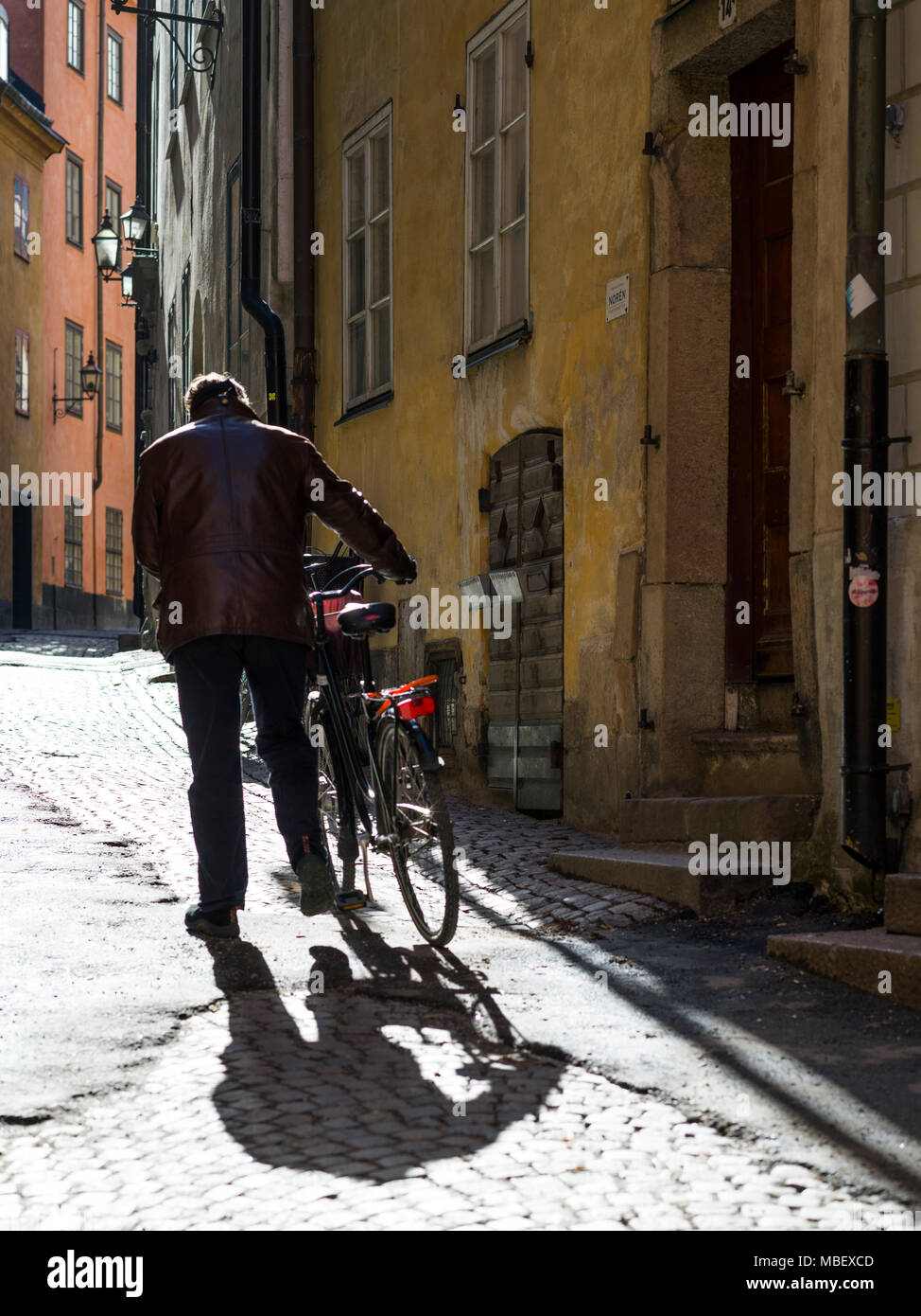 Man walking with bicycle in street, Gamla Stan, Stockholm, Sweden Stock Photo