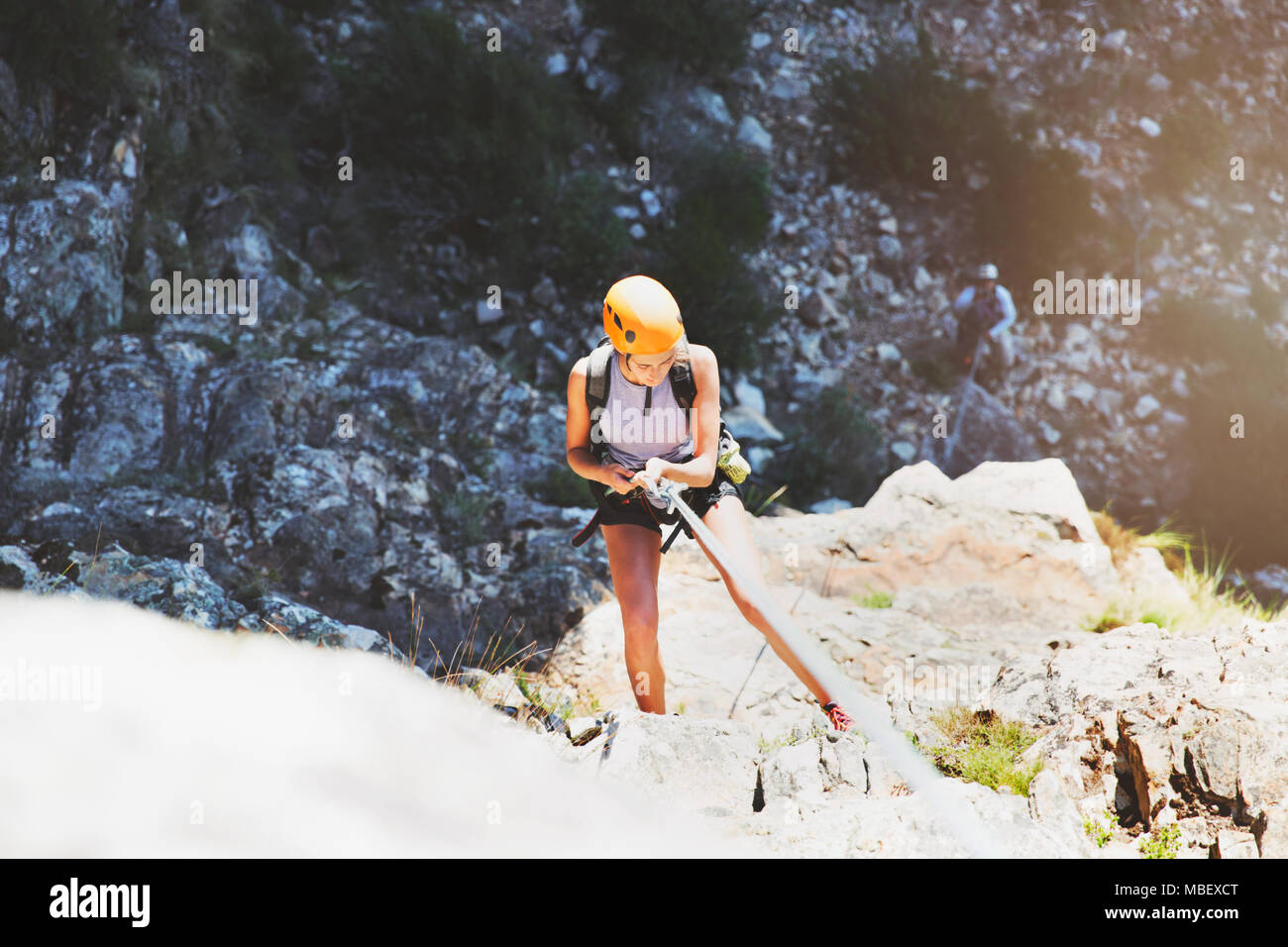 Female rock climber rappelling rock Stock Photo