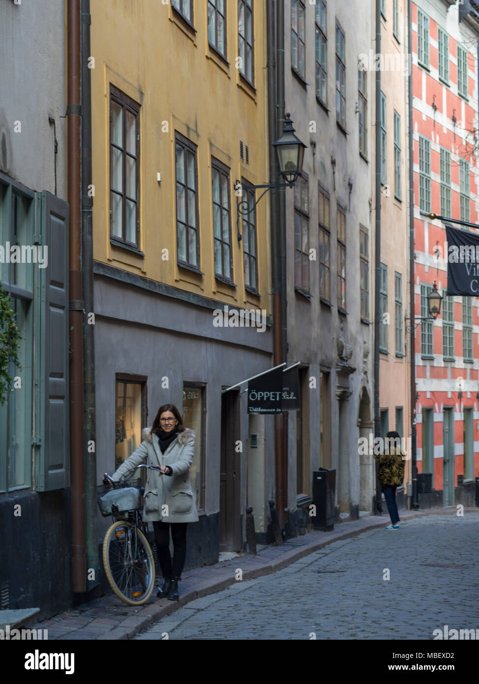 Woman standing with bicycle in street, Gamla Stan, Stockholm, Sweden Stock Photo