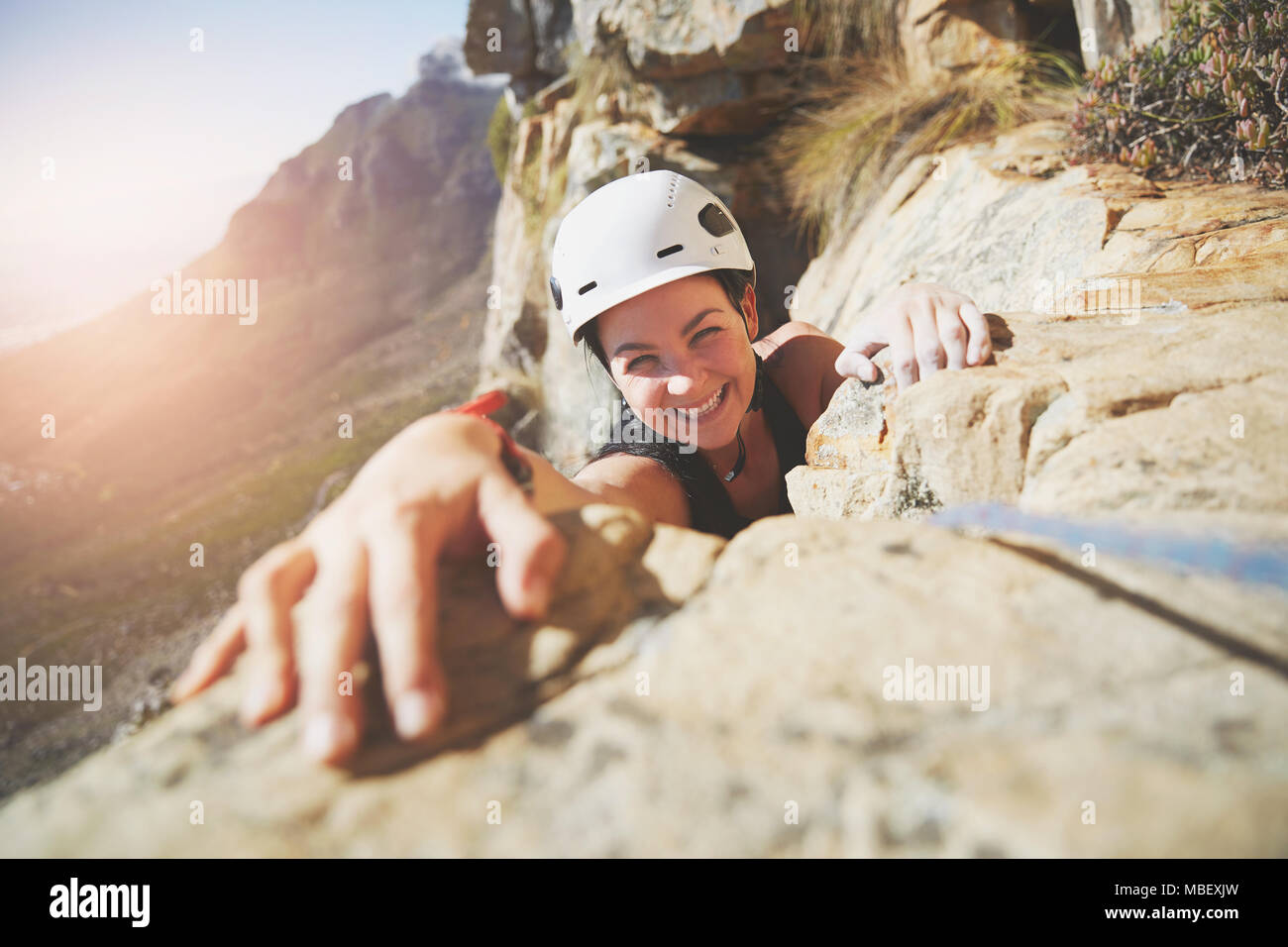 Portrait smiling, confident rock climber reaching for rock Stock Photo