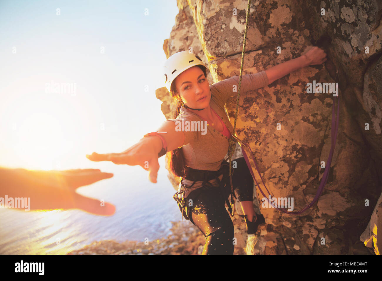 Female rock climber reaching for helping hand Stock Photo