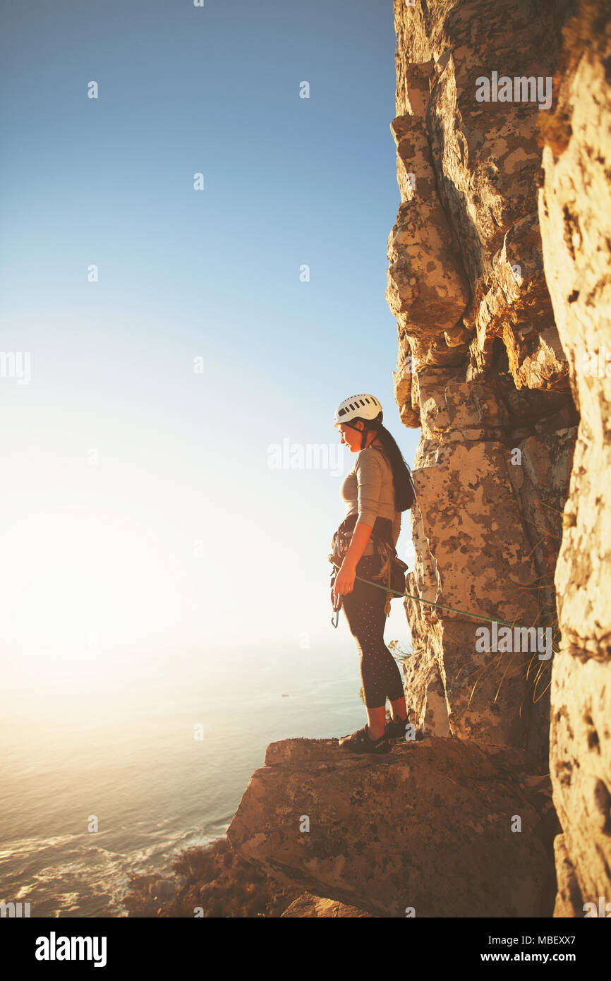Female rock climber looking at sunny ocean view Stock Photo