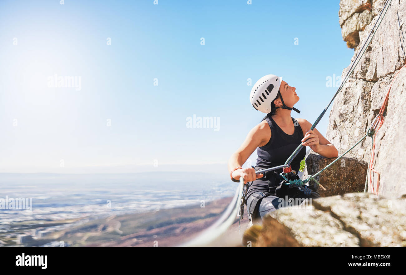 Female rock climber holding rope, looking up Stock Photo
