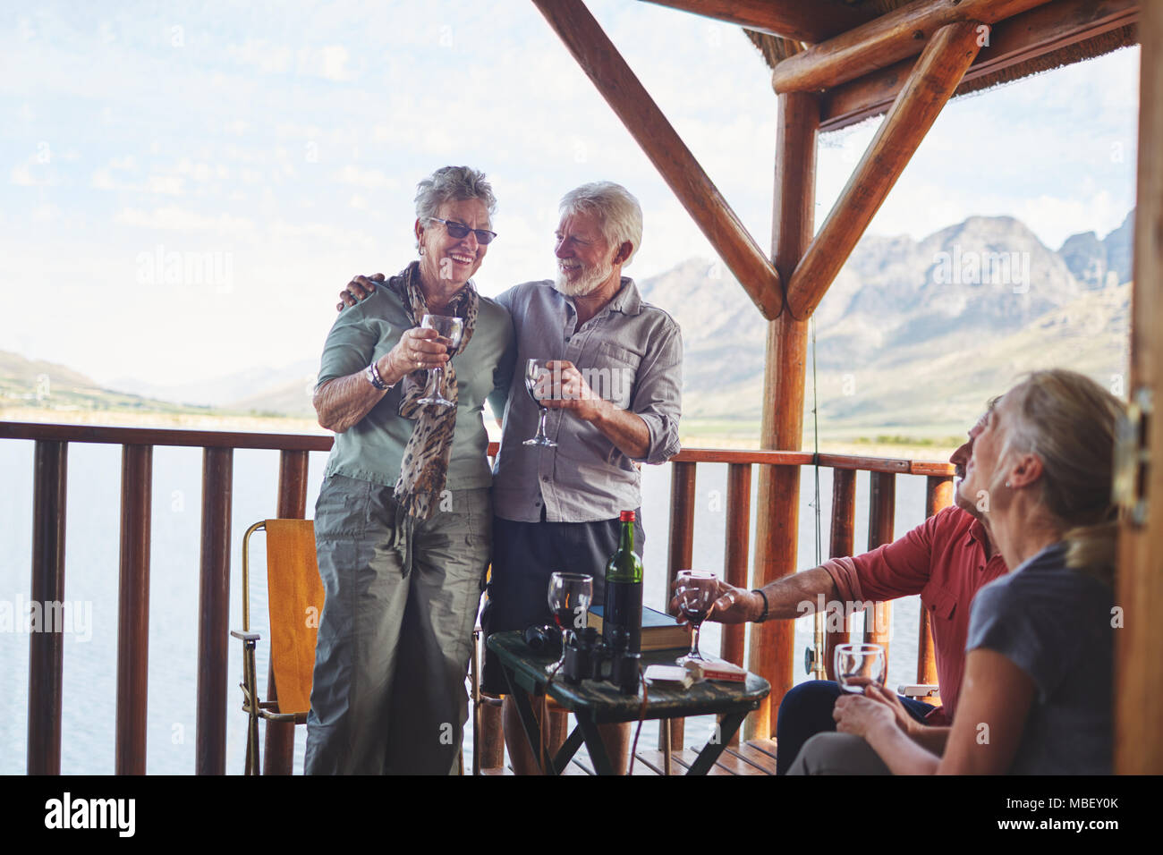 Happy active senior couples drinking wine on summer balcony Stock Photo