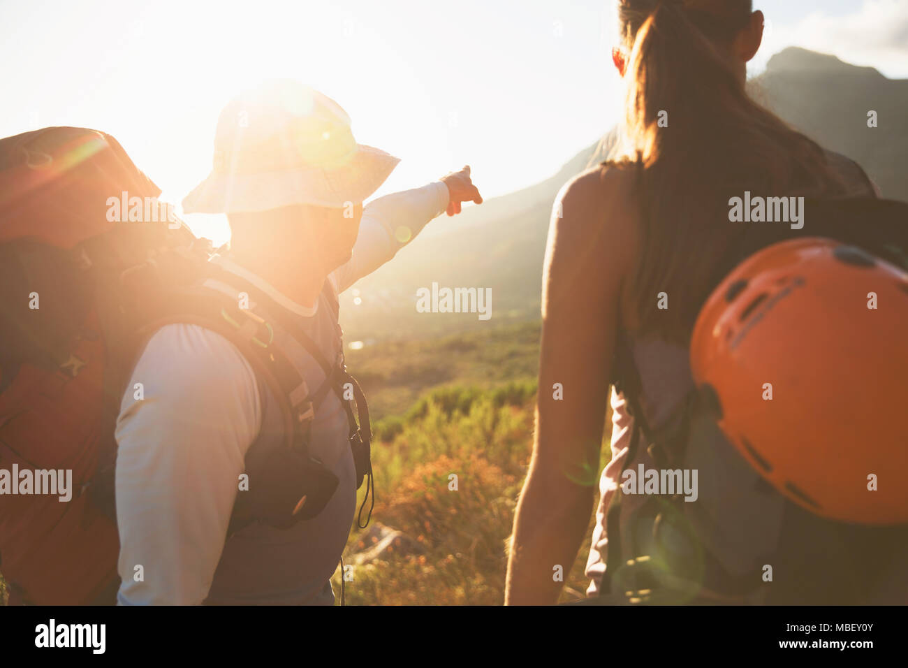 Rock climbers pointing to sunny mountain Stock Photo