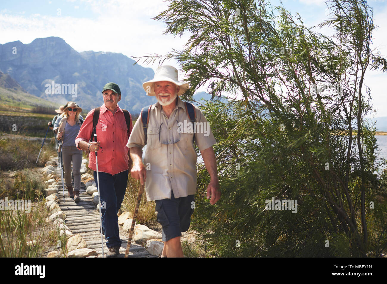 Active senior friends hiking along footpath Stock Photo