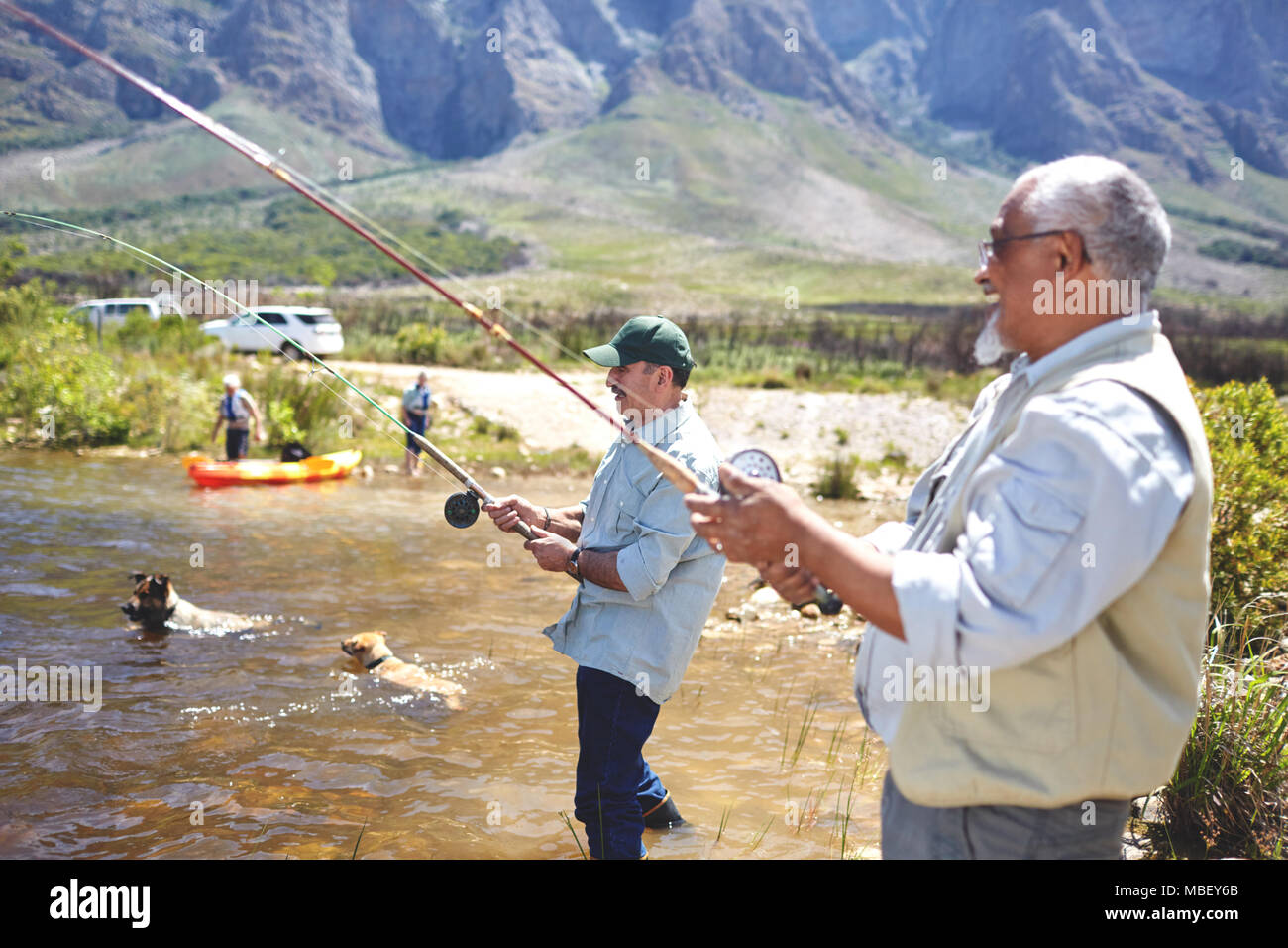 Active senior men friends fishing at sunny summer lake Stock Photo