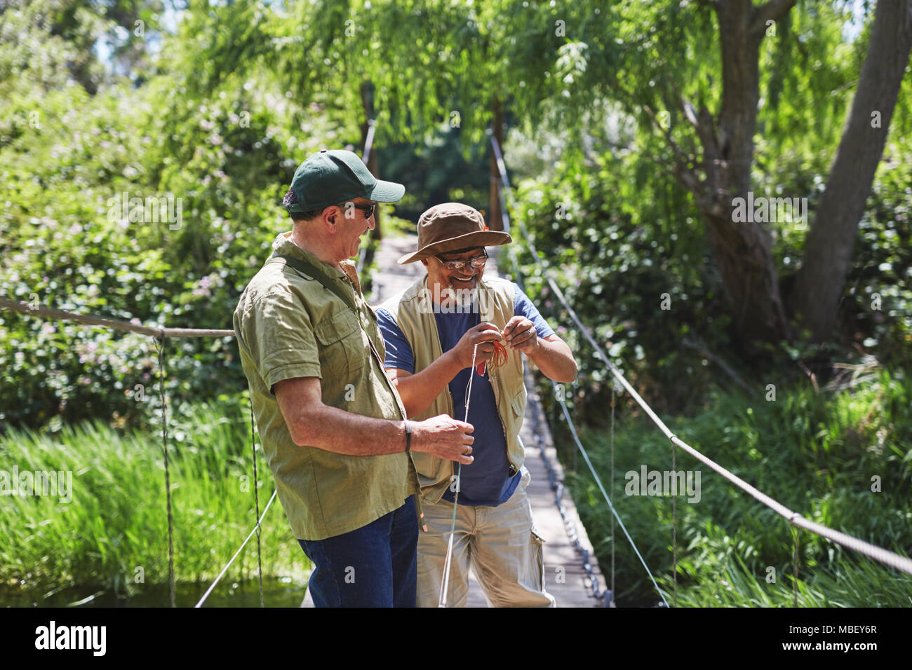 Active senior men friends fishing on footbridge Stock Photo