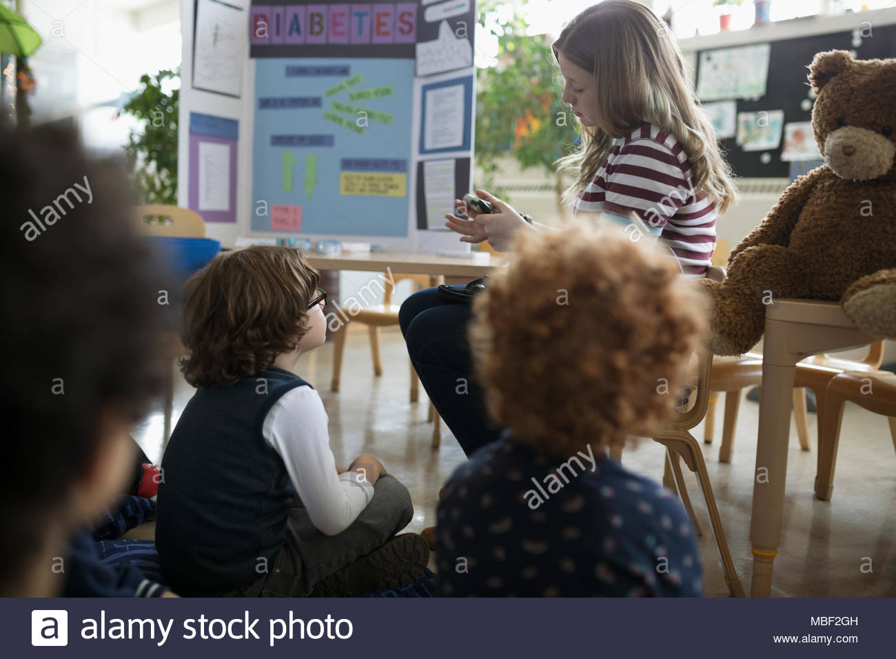 Preschool students watching tween girl demonstrating diabetes insulin check during presentation Stock Photo