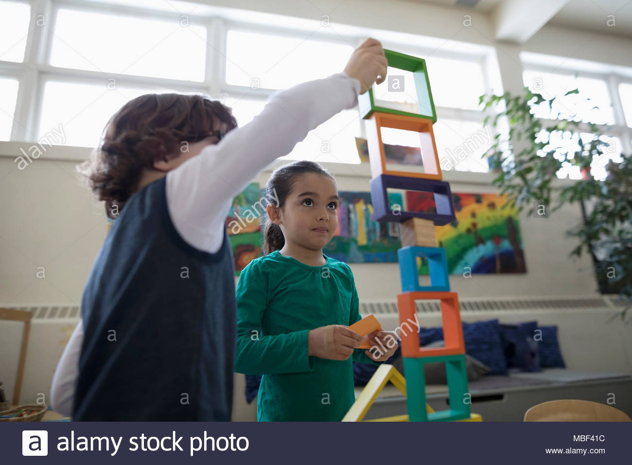 Preschool boy and girl stacking building blocks in classroom Stock