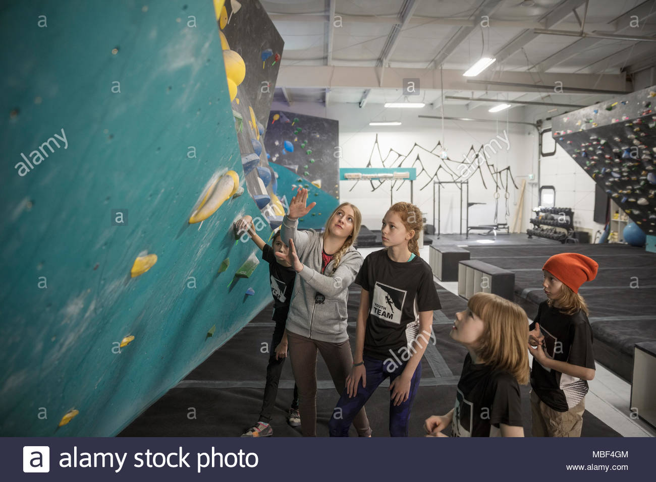 Female instructor teaching girl rock climbing students at climbing wall