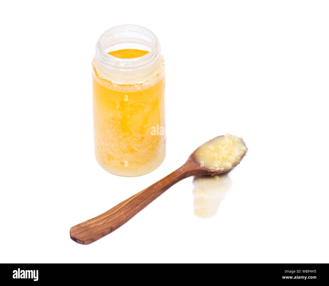Clarified butter ghee in wooden spoon and plastic jar isolated on white background Stock Photo