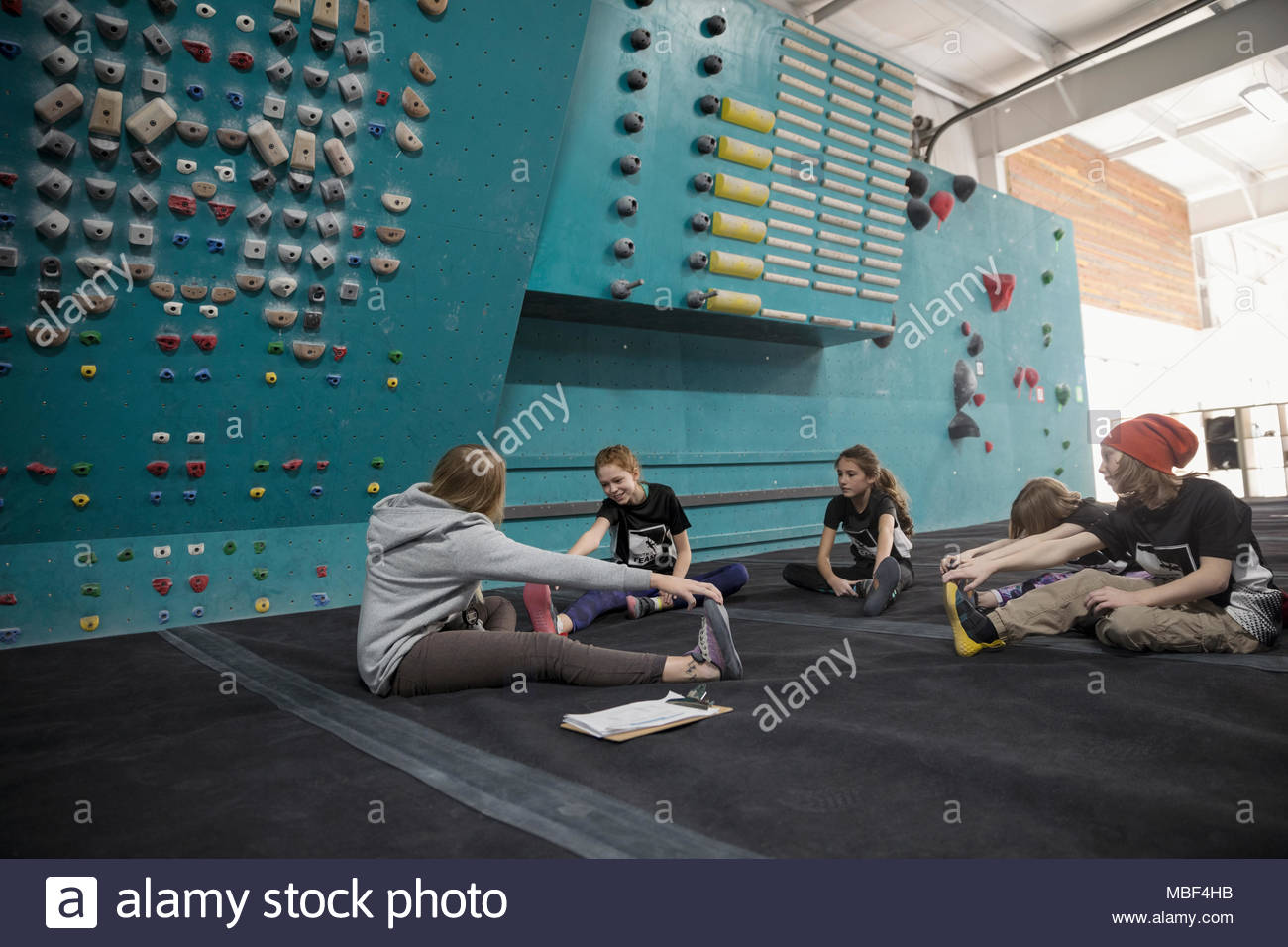 Female instructor and girl rock climber students stretching legs