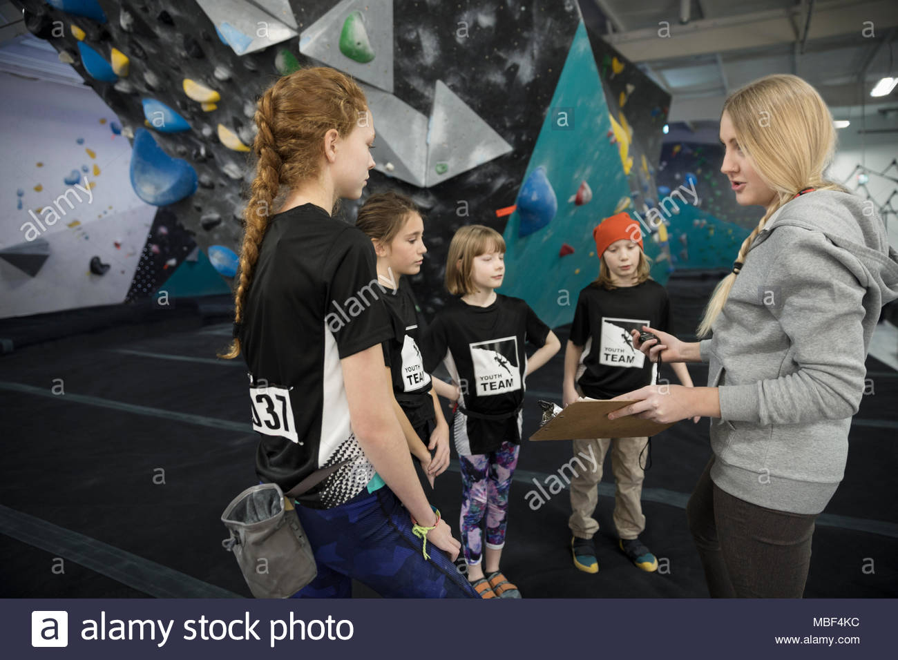 Female instructor with clipboard giving lesson to rock climbing