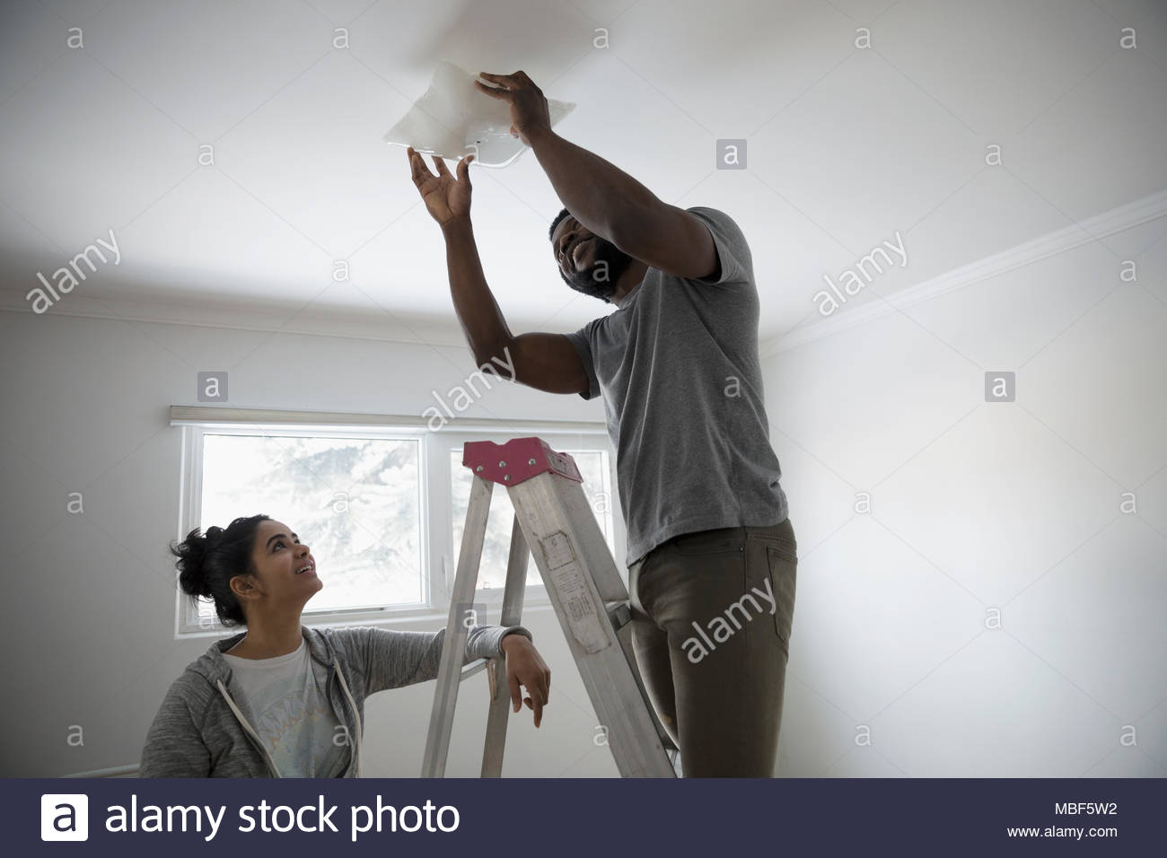 Young Couple Moving In Replacing Light Fixture Diy Stock Photo