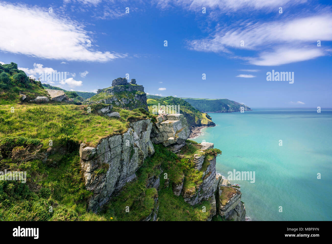 Hiker resting on a headland in the Valley of the Rocks on South West coast path, Devon, England, UK Stock Photo