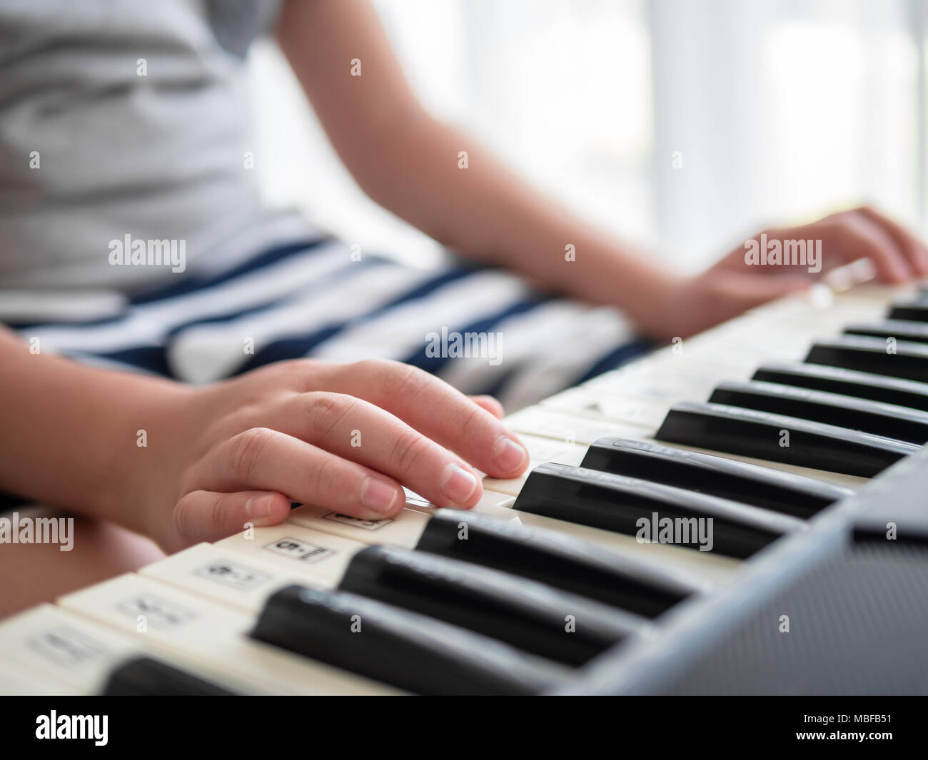 Boy playing keyboard piano near window at home Stock Photo Alamy