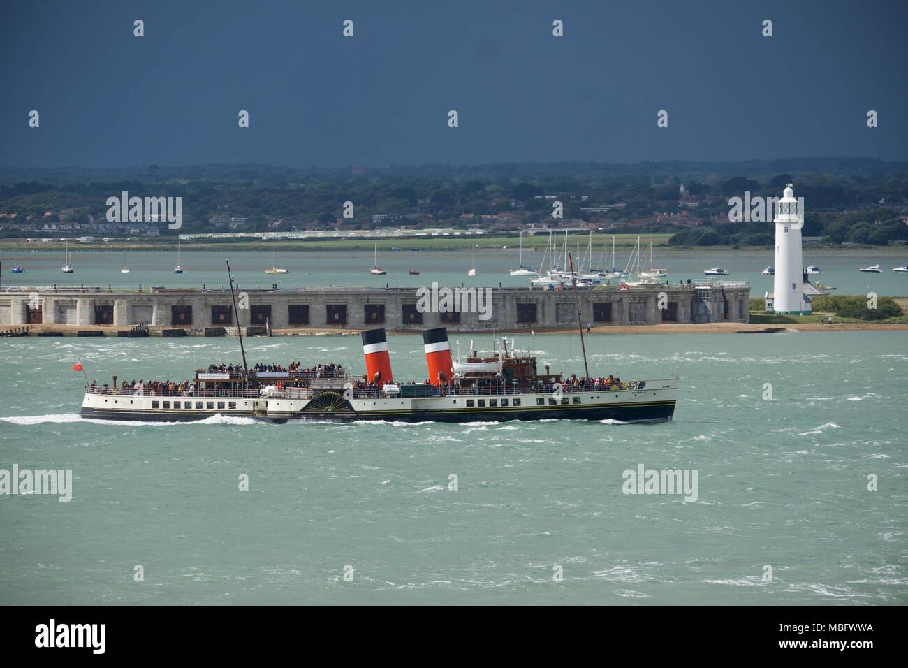 PS Waverley the last paddle steamer passenger ship on the Solent passing Hurst Spit, lighthouse and Hurst Castle on a day with a dark stormy sky Stock Photo