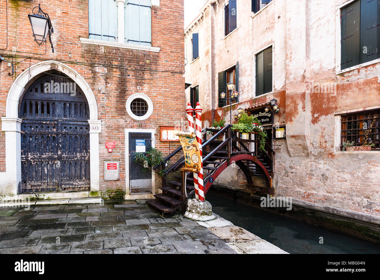 View of tiny bridge with flowers and lampposts into a typical Venice