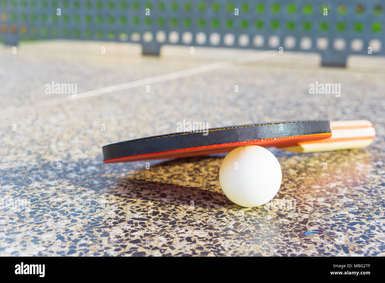 Close-up of a Ping-pong paddle with a table-tennis white ball on a table-tennis stone table with copy space. Sport and leisure concept Stock Photo
