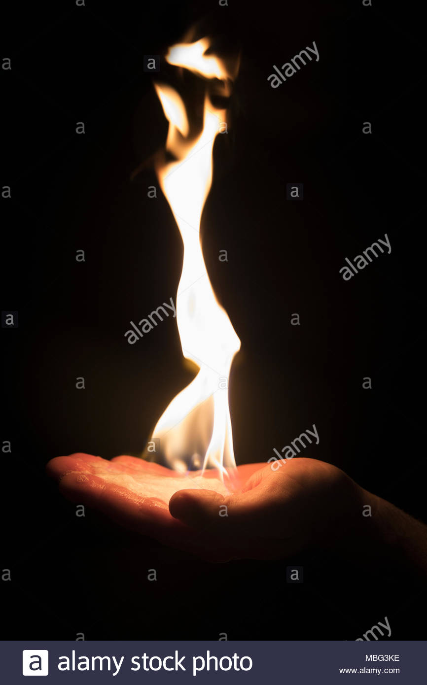 Hand holding creative, inspiring flame on black background Stock Photo