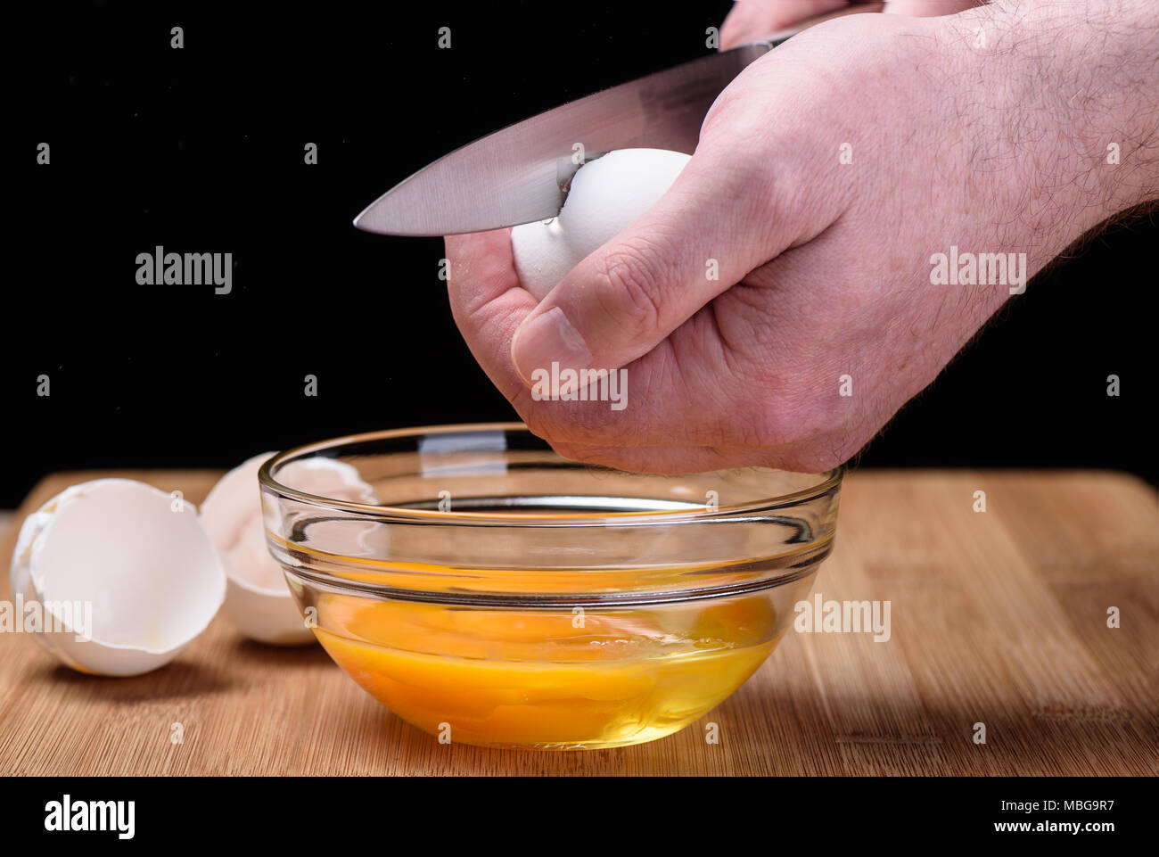 Destruction of a chicken white egg with a knife in male hands Stock Photo