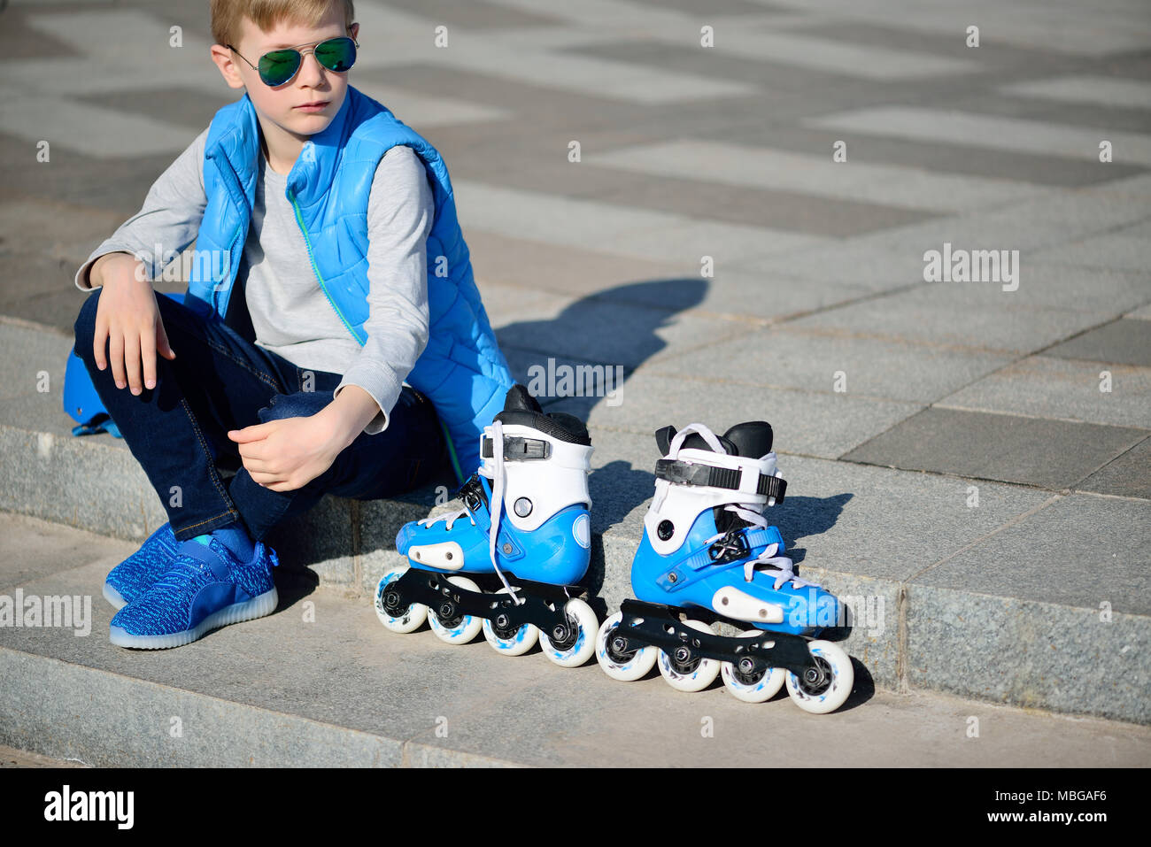 Boy siting with inline roller skates at outdoor skate park Stock Photo