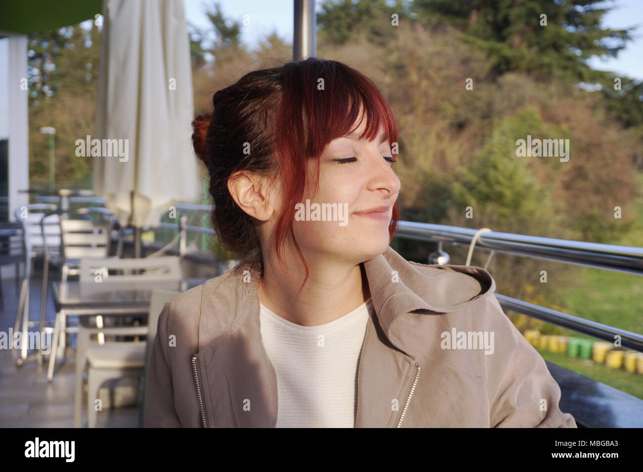 Happy young woman sitting on the cafe terrace and satisfied thinking ...