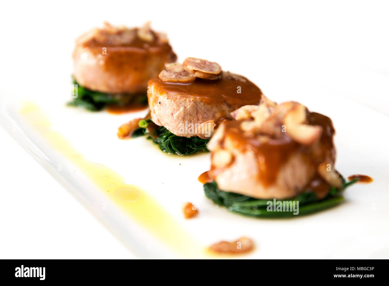 lateral shot of three veal fillet medallions with white wine sauce and