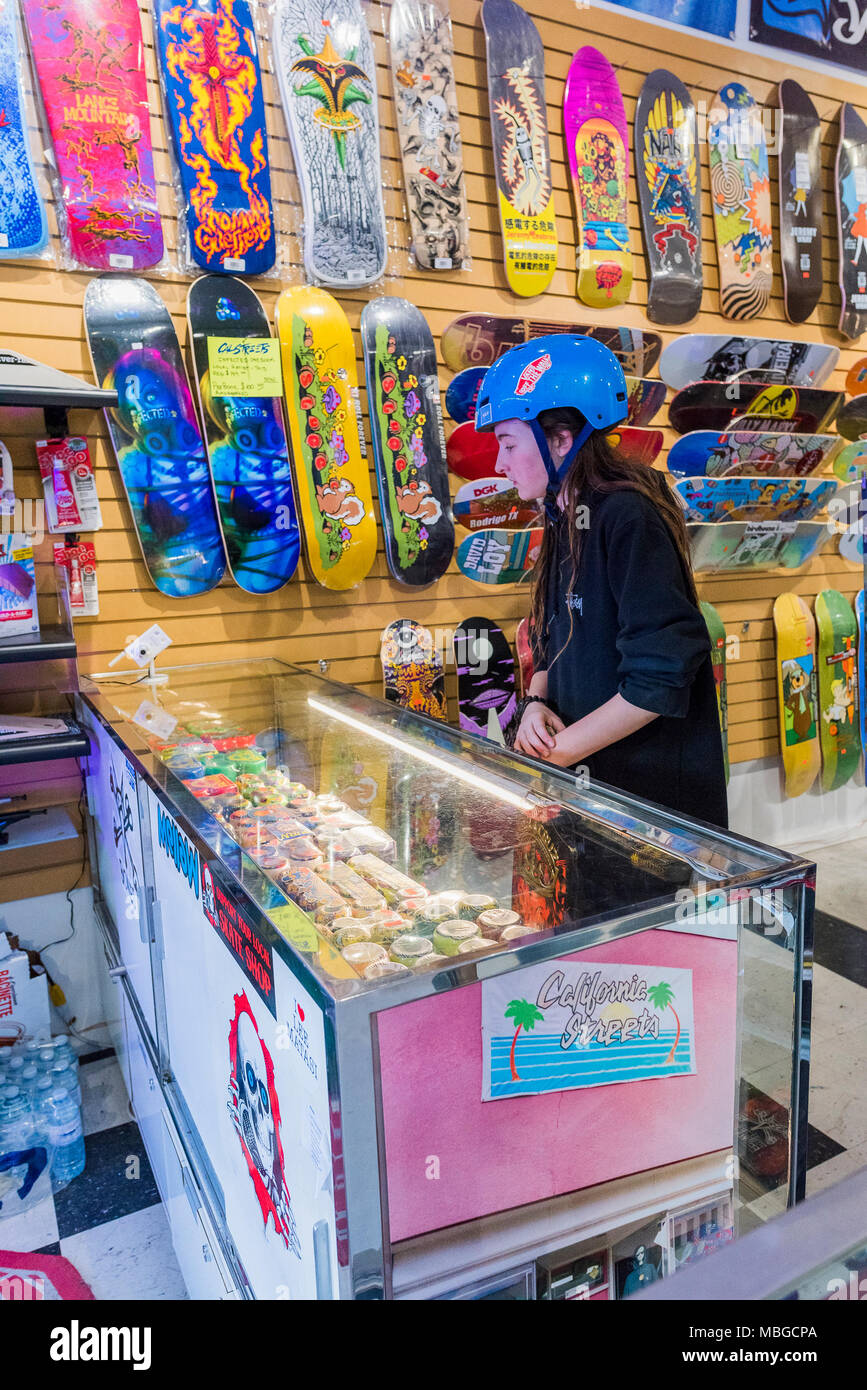 Young teenage boy with long hair checks out new wheels in skateboard