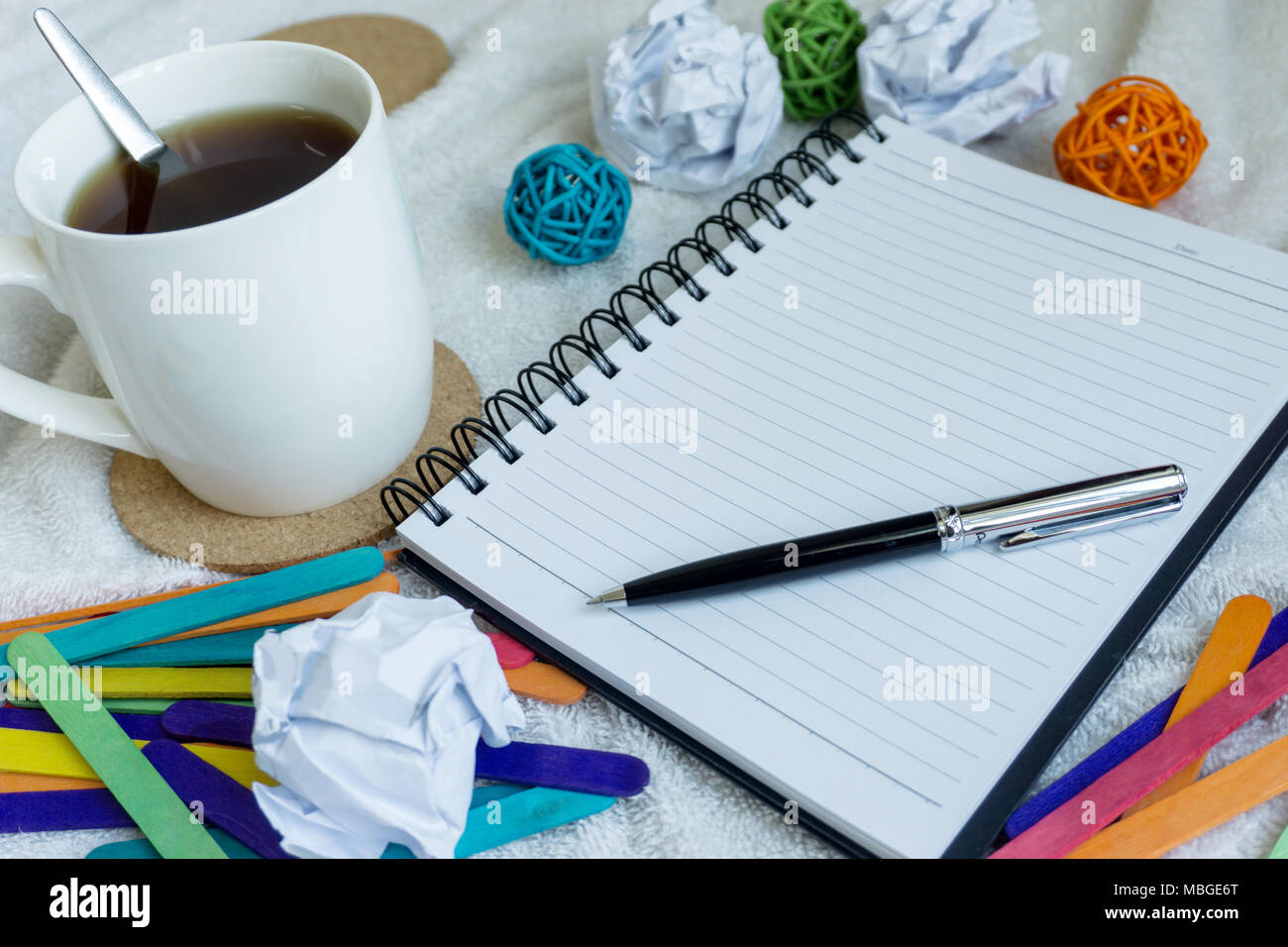 A mug of coffee, note pad and pen on top of white cloth Stock Photo