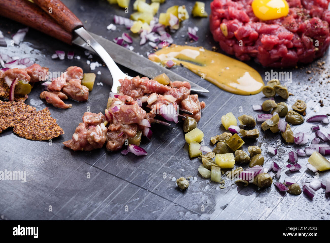 Steak tartare preparation. Raw ground beef dish with onion, mustard