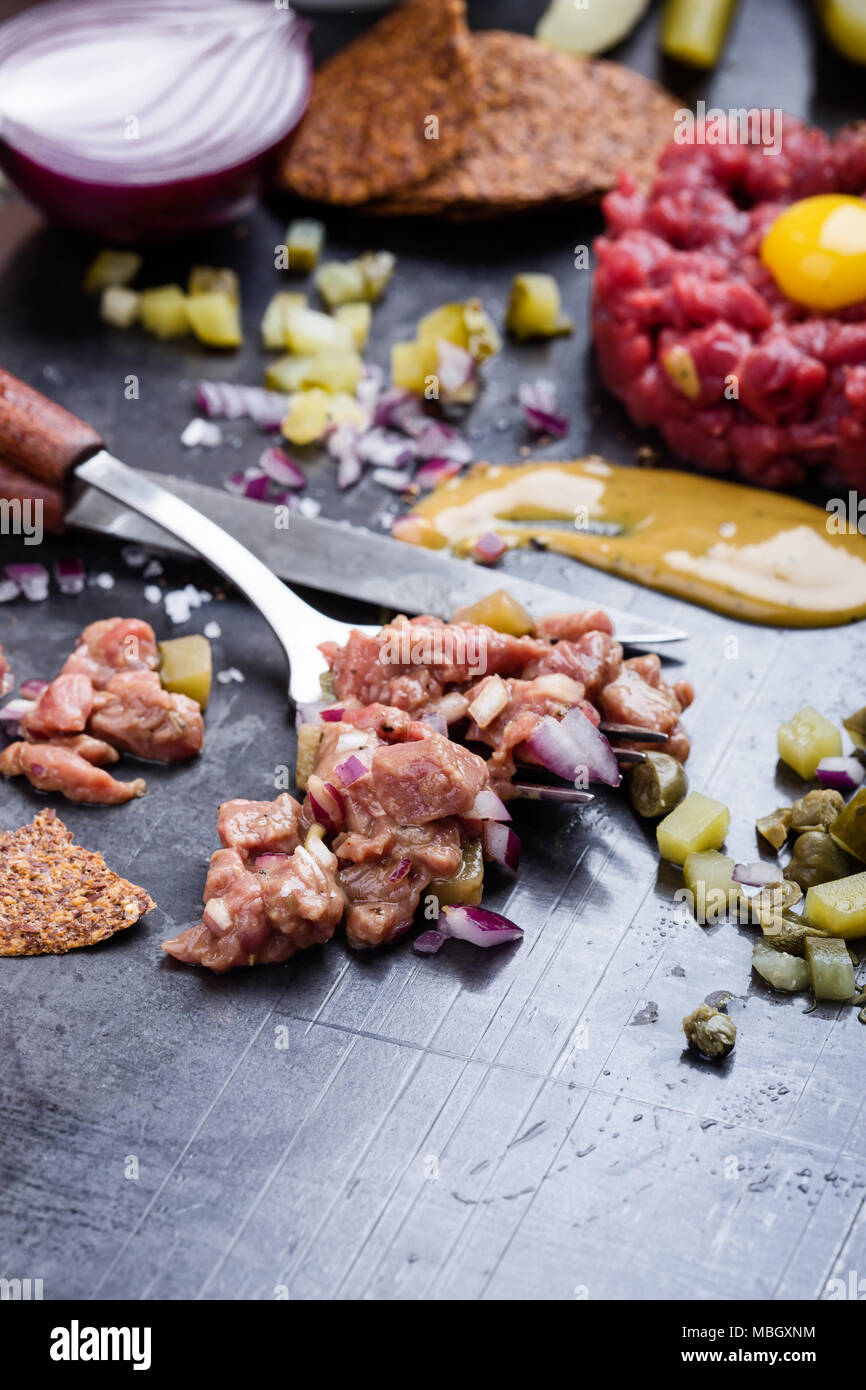 Steak tartare preparation. Raw ground beef dish with onion, mustard