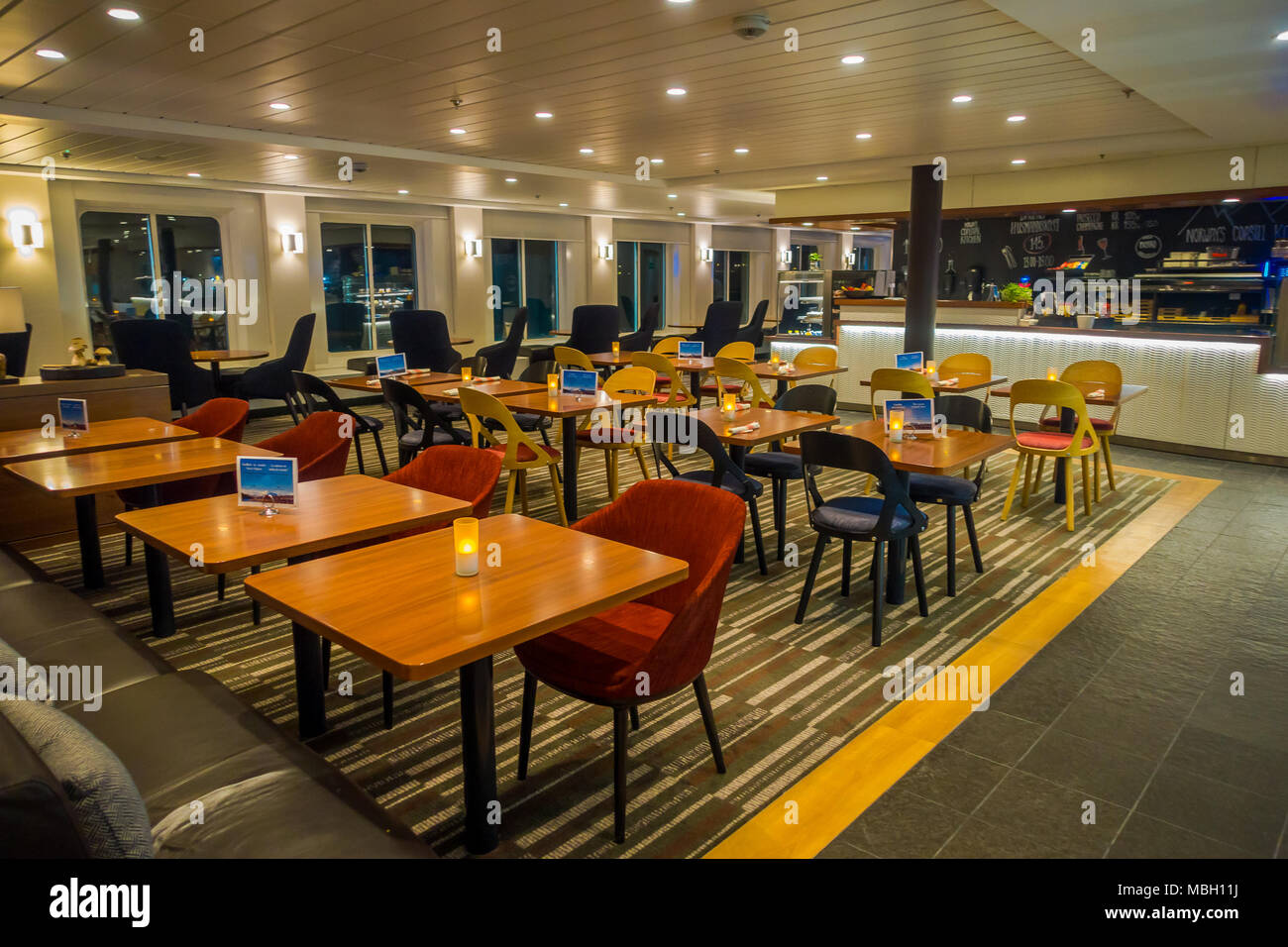 ALESUND, NORWAY - APRIL 04, 2018: Indoor view of dinning tables with confortable chairs with candles inside of Hurtigruten voyage in cruise Stock Photo
