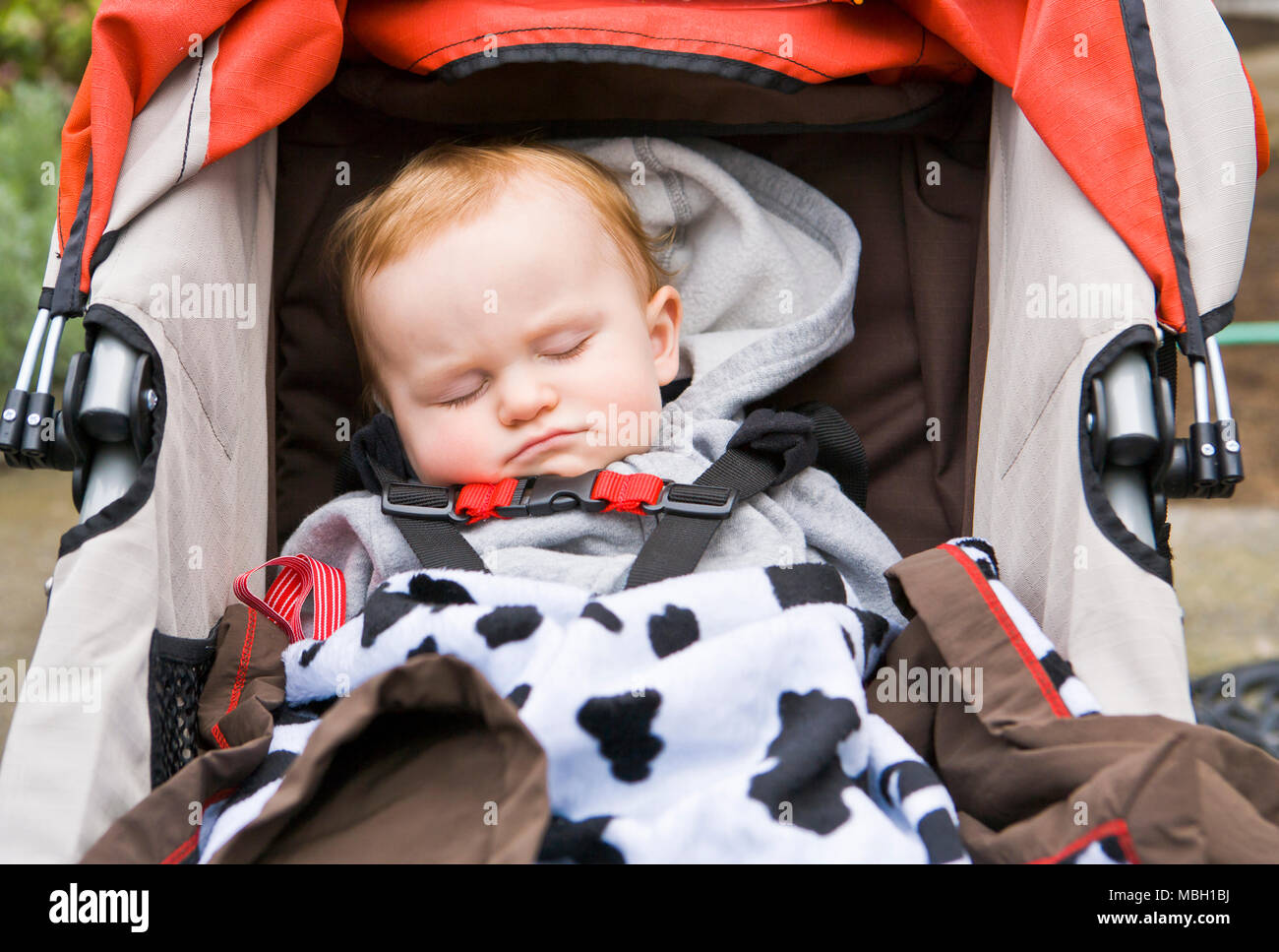 A 10 month old baby boy asleep in his stroller. Stock Photo