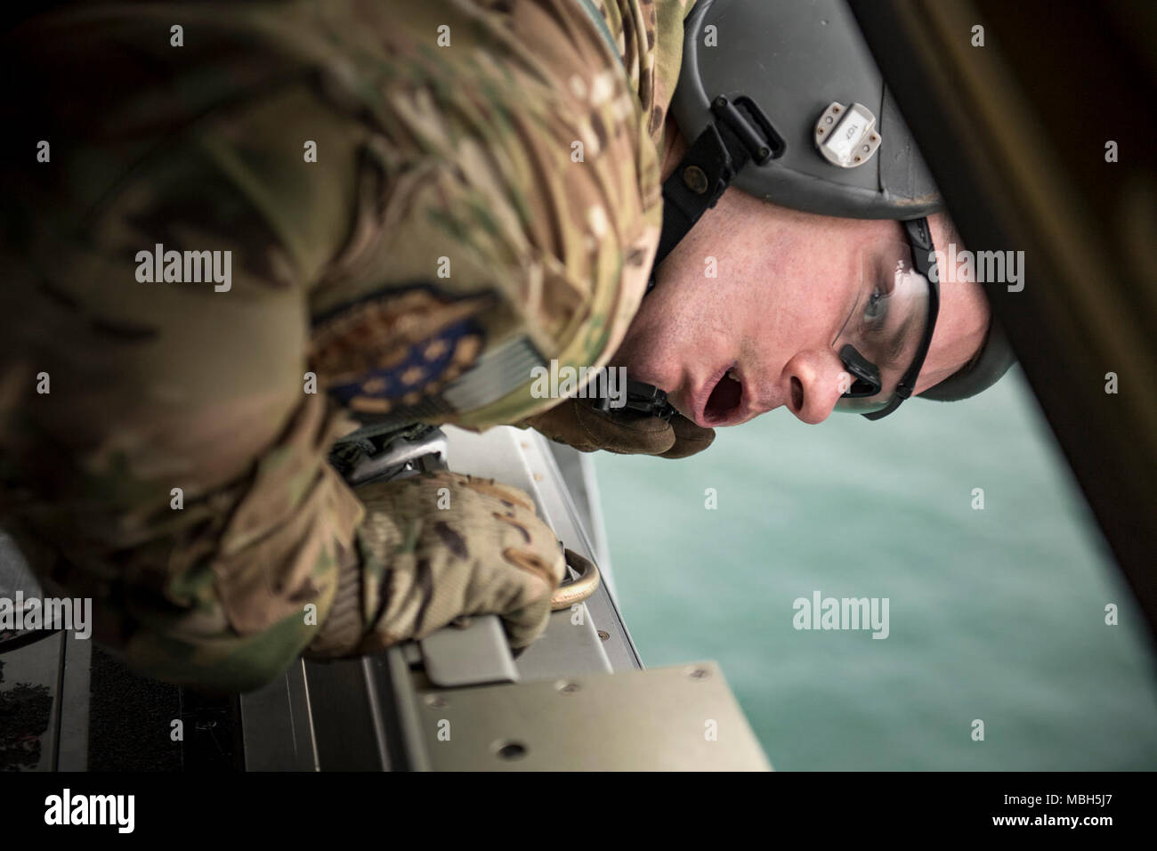 Staff Sgt. James Baker, 71st Rescue Squadron loadmaster, scans the waters below during pyrotechnic employment training, March 30, 2018, in the skies over the Gulf of Mexico. The 71st RQS utilizes various pyrotechnics and sea-dye to assist in over-water rescue efforts. Stock Photo