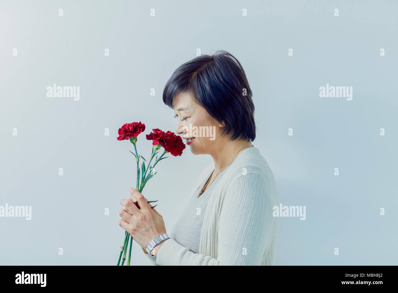 Japanese senior woman holding red roses Stock Photo
