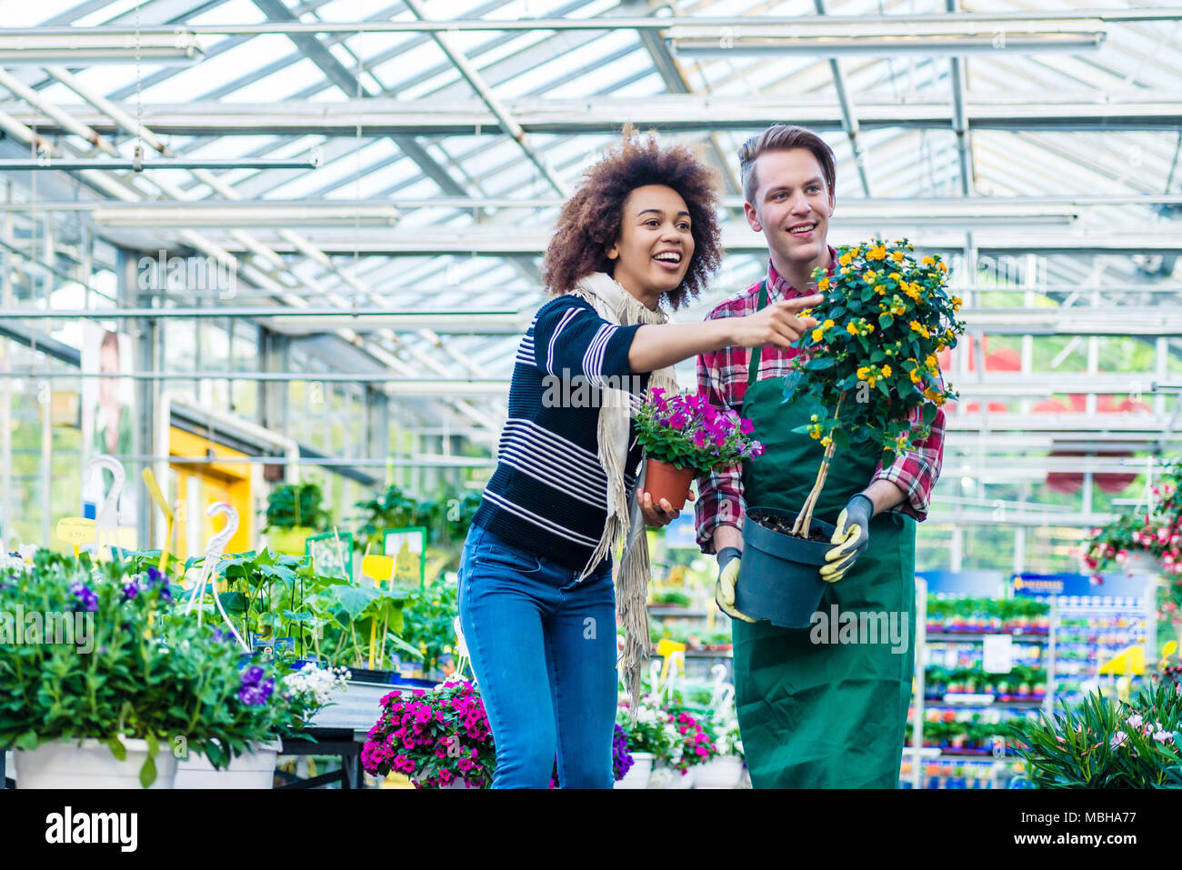 Handsome worker helping a customer with the purchase of a houseplant Stock Photo