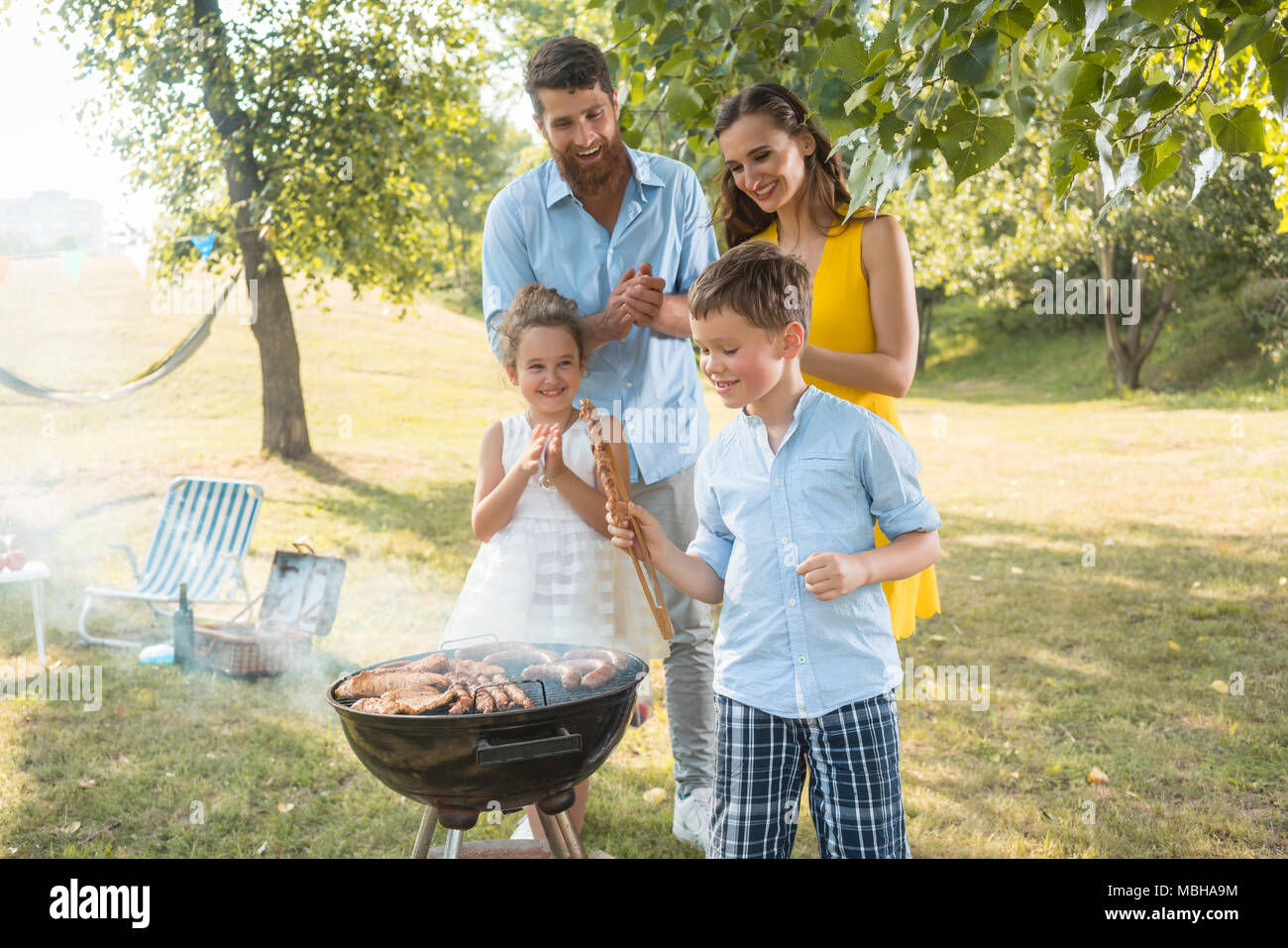 Portrait of happy family with two children standing outdoors near barbecue Stock Photo