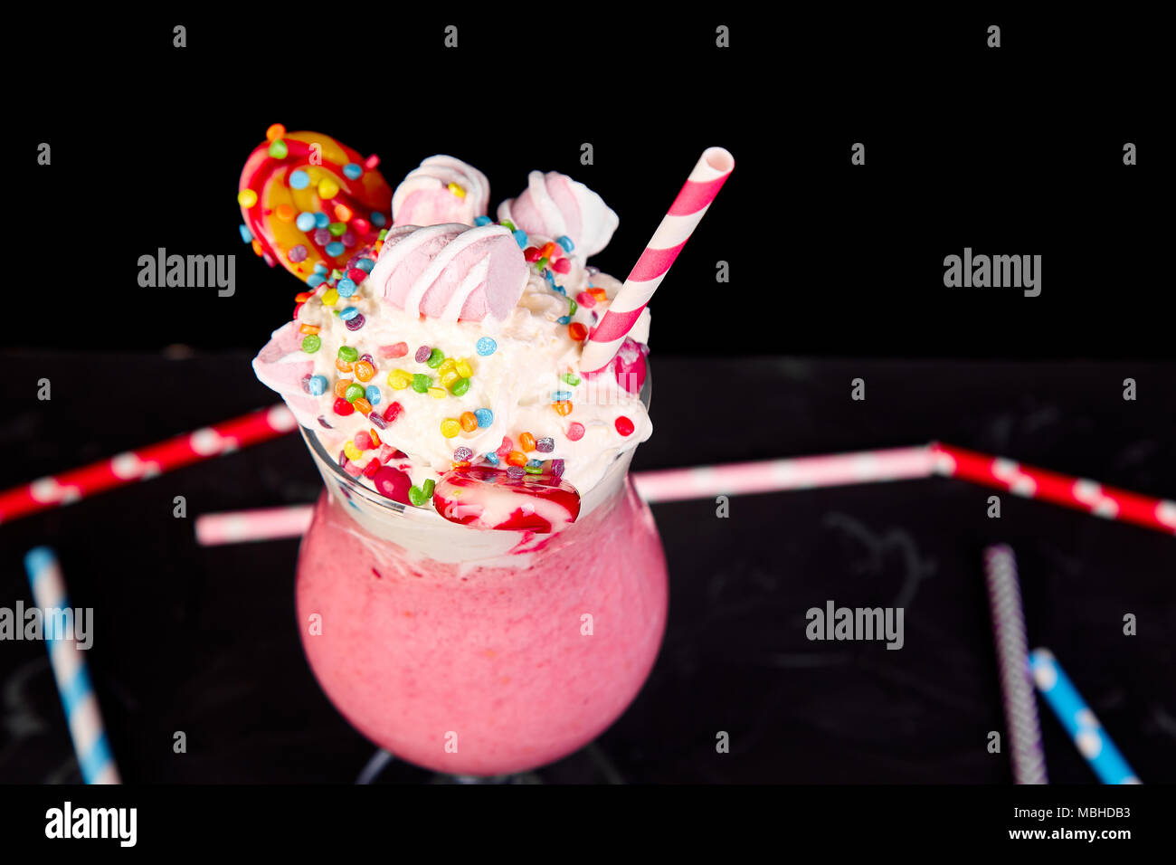 https://c8.alamy.com/comp/MBHDB3/pink-extreme-milkshake-with-berry-rasberry-strawberry-candy-marshmallow-lollipops-on-black-background-crazy-freakshake-copy-space-food-trend-o-MBHDB3.jpg