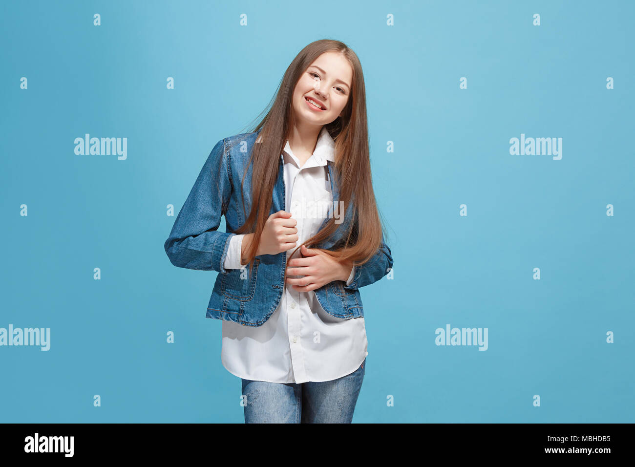 The happy teen girl standing and smiling against blue background Stock ...